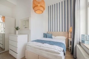 A bedroom with a bed, bedside table, lamp, and a mirror.