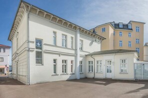 A building with a white facade, multiple windows, and a corner entrance.