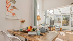 A modern dining area with a wooden table, chairs, and a fruit bowl.