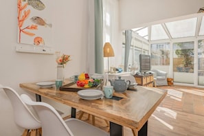 A modern dining area with a wooden table, chairs, and a fruit bowl. - Cozy apartment in Heringsdorf with terrace - 150 m to the beach - Villa (Heringsdorf)