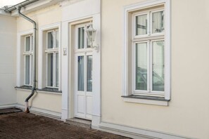 Ein Gebäude mit drei Fenstern, einer Tür und einem Laternenpfahl.