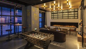 Un espace bar moderne avec un baby-foot, des tabourets de bar et une cheminée.