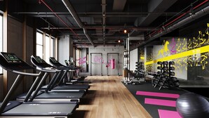 Une salle de sport équipée de tapis de course, de poids et de ballons d’exercice.