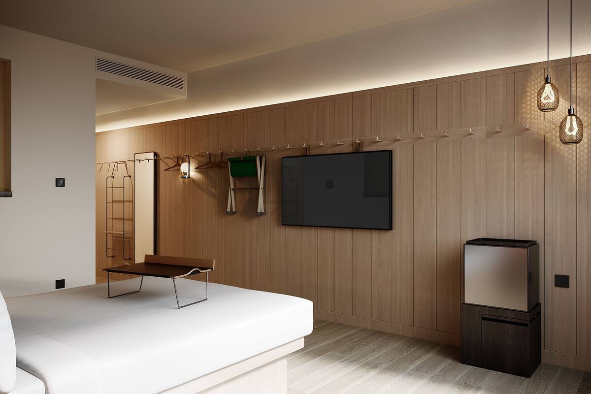A modern room with a minimalist design, featuring a sofa, a flat-screen TV, and a small table.