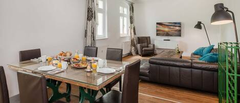 Un coin repas avec une table en verre, des chaises, des aliments pour le petit-déjeuner et un canapé en arrière-plan.