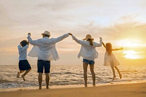 A family of four at the beach during sunset.