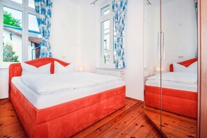 Ein Schlafzimmer mit einem Bett, einem Spiegel und einem Fenster mit Vorhängen.