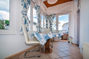 Un coin repas avec une table dressée pour deux personnes, une chaise et une vue sur l’extérieur.