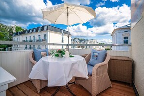 A balcony with wicker furniture, a table with a white tablecloth, and an umbrella.