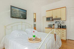 Ein Bett, eine Champagnerflasche, eine Mikrowelle und eine kleine Küchenzeile mit Holzausstattung.