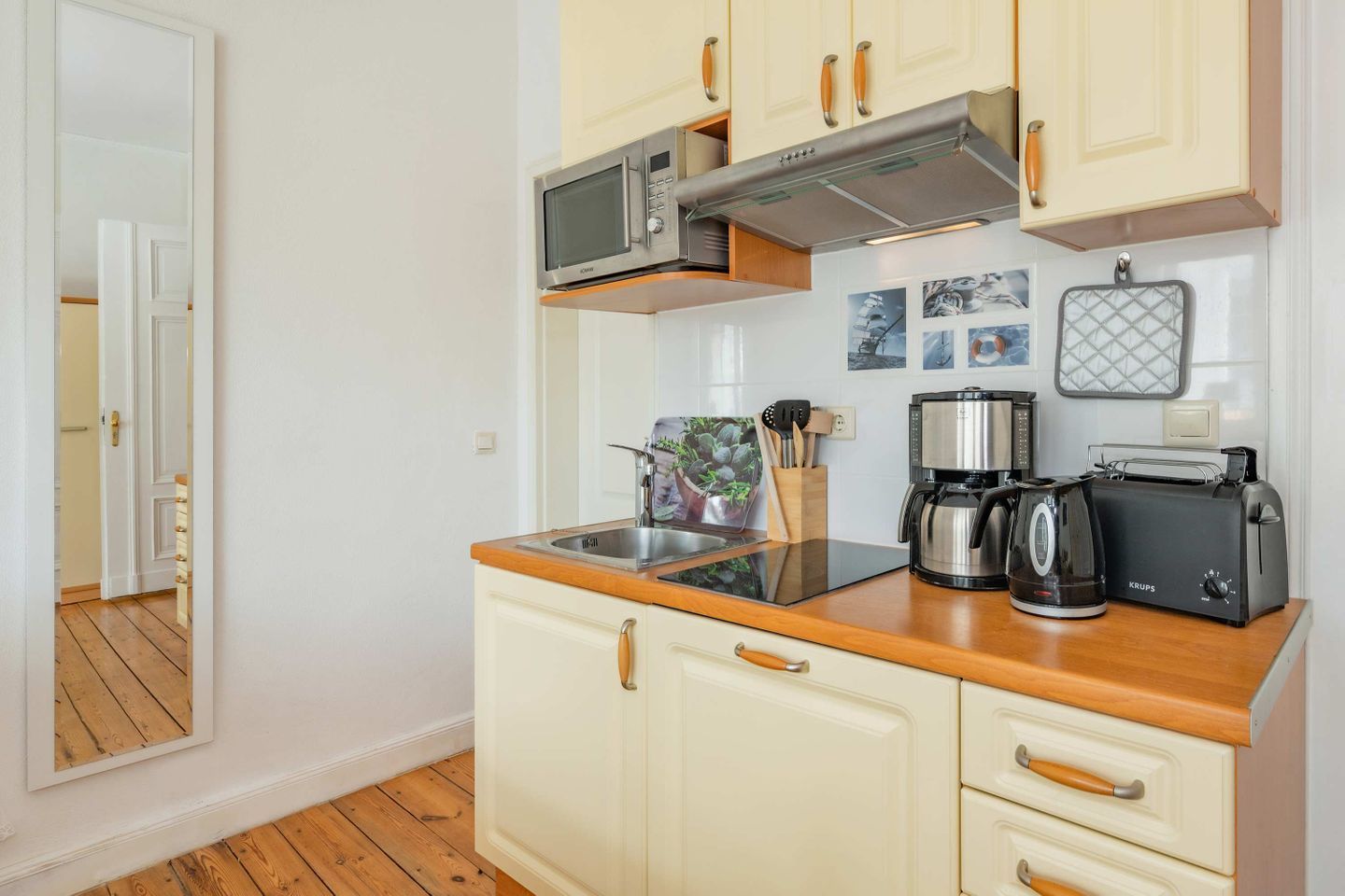 A compact kitchen with a microwave, coffee maker, toaster, and wooden countertop.