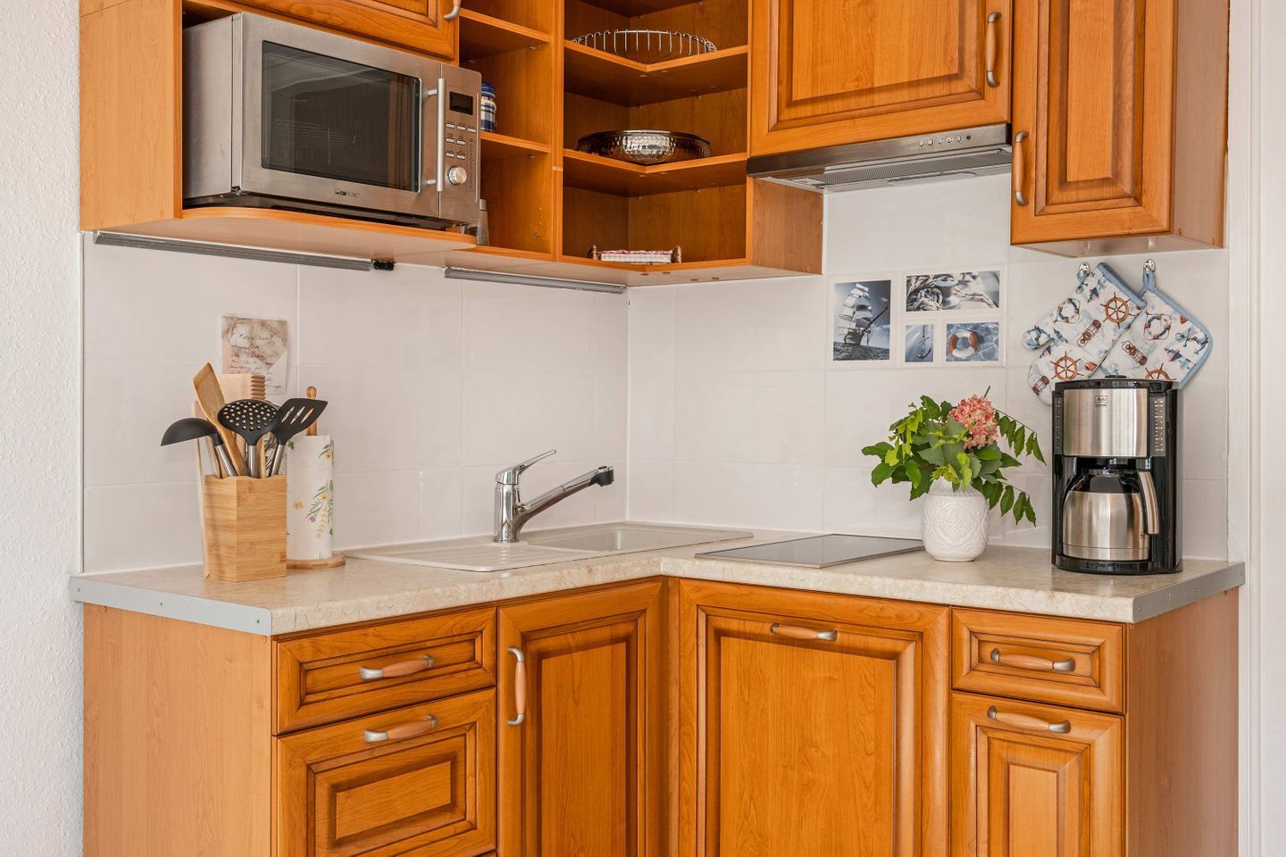A kitchen with wooden cabinets, a microwave, a coffee maker, and a sink.
