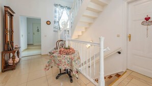 A staircase with white railings, a floral table with a glass top, and a wooden cabinet with a mirror. - "Seeadler" Vacation Rental – A Baltic Sea Getaway in Heringsdorf, 200 m from the beach - (Heringsdorf)