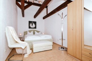 Ein Schlafzimmer mit Bett, Stuhl, Kleiderschrank und Garderobe.