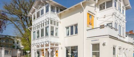 A white building with multiple windows, a balcony, and a sign reading 'SEESTRASSE 7'.