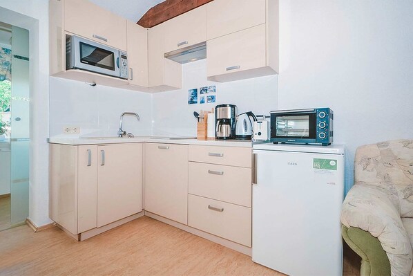 Una cocina compacta con microondas, cafetera y un refrigerador pequeño.