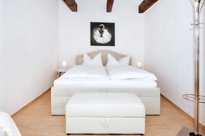 A bedroom with a bed, bedside tables, a nightstand, a floor lamp, and a framed picture on the wall.