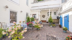 Un cortile con piante in vaso, posti a sedere all'aperto e un balcone.