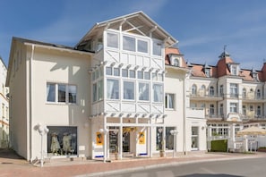 Ein Gebäude mit einer markanten weißen Fassade, großen Fenstern und einem Balkon.