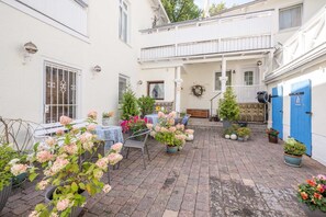 Ein Innenhof mit Blumentöpfen, Sitzgelegenheiten im Freien und einem Balkon.