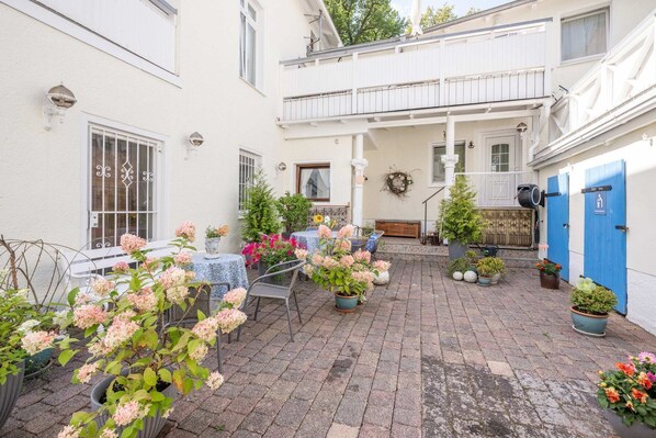 A courtyard with potted plants, outdoor seating, and a balcony.