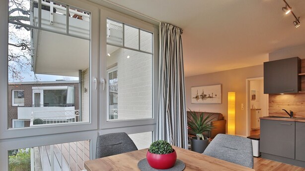 A modern apartment with a dining area, kitchen, and large windows. - Bädervilla am Höppnerweg Apartment 5 - Bädervilla am Höppnerweg (Timmendorfer Strand)
