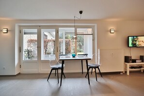 Un comedor con una mesa y sillas, una lámpara colgante y un televisor sobre una estantería.