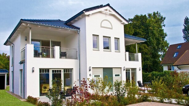 A two-story house with a balcony, a garage, and a driveway.