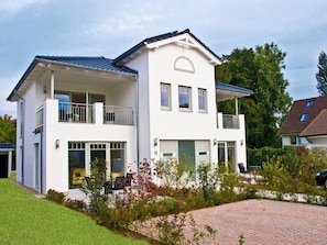 Una casa a due piani con un balcone, un garage e una strada privata.