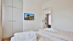 A hotel room with two beds, a TV mounted on the wall, and a wardrobe. - Villa Marisol Apartment 4 - Villa Marisol (Timmendorfer Strand)