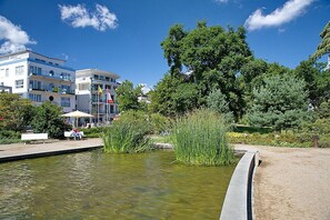 Un cadre paisible au bord du lac, avec une vue dégagée sur des bâtiments modernes, une jetée en bois et une végétation luxuriante.