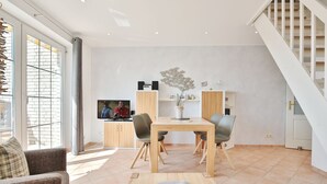 Un salon moderne comprenant un coin repas, un téléviseur et un escalier.