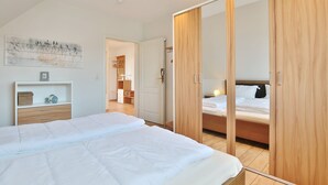 Une chambre à coucher avec un grand lit, une armoire en bois et une petite table de chevet.
