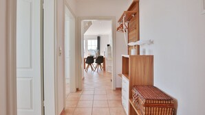 Un couloir qui mène à une salle à manger, avec une table et des chaises, et une vue sur la ville en arrière-plan.