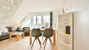 Un salon moderne avec un coin repas, de grandes fenêtres et un escalier.