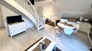 Eine moderne Wohnung mit Treppe, Essbereich, Küche und Wohnzimmer mit Fernseher.