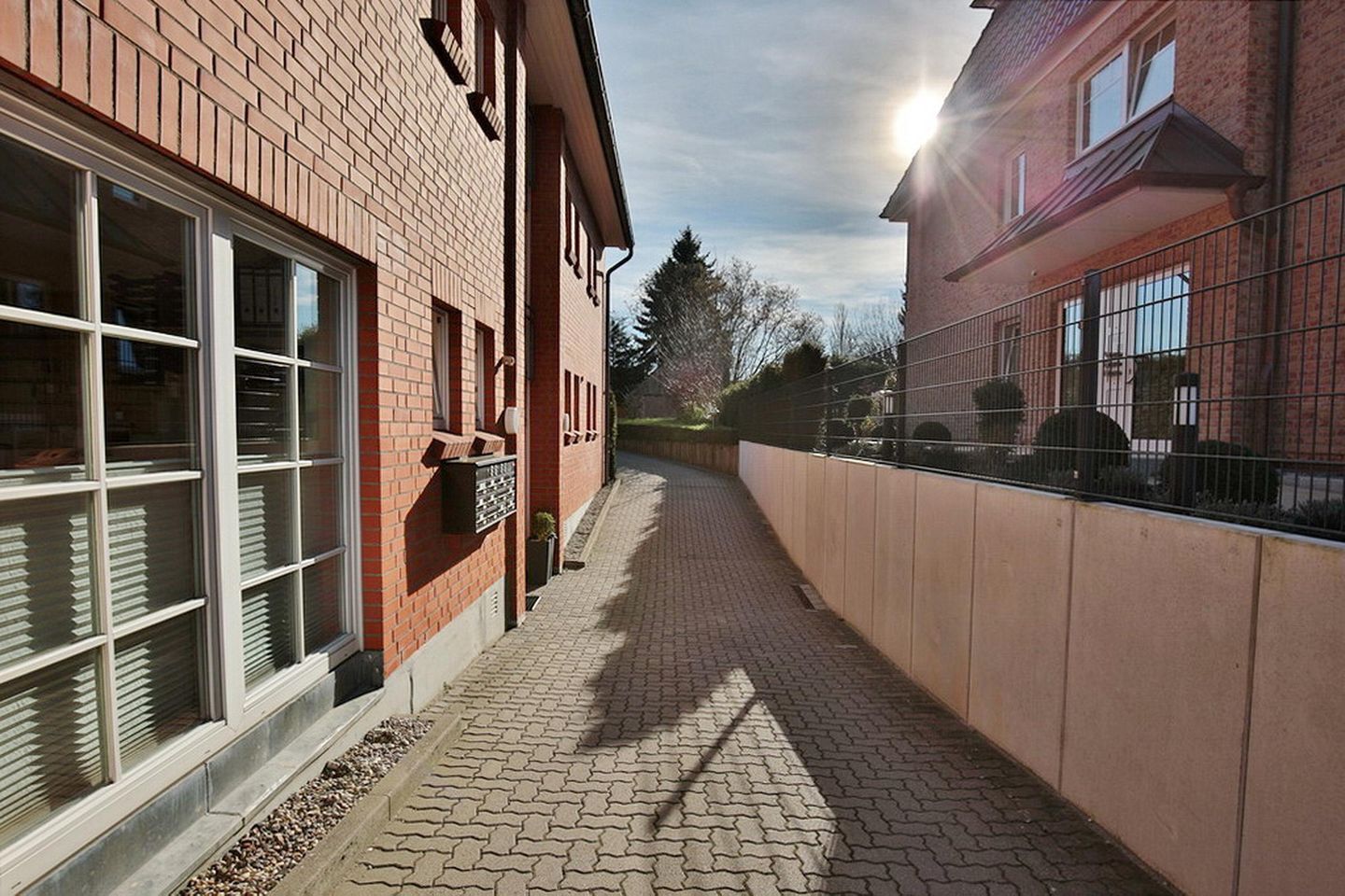 A brick building with large windows and a paved walkway.