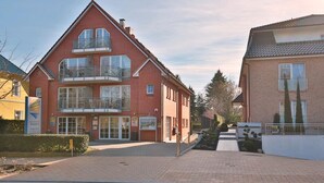 A two-story building with a red brick facade, a balcony on the second floor, and a small garden area in front. - Haus Parkblick Apartment 10 - Haus Parkblick, Timmendorfer Strand (Timmendorfer Strand)