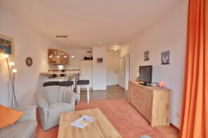 A modern living room with a sofa, coffee table, and a TV on a wooden cabinet. - Carpe Diem Appartement 141 - Carpe Diem (Timmendorfer Strand)