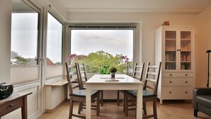 Un espace repas comprenant une table, des chaises, un buffet et une vue par la fenêtre.
