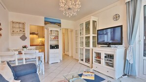 A modern living room with a sofa, a glass coffee table, a TV, and built-in cabinets. - Carpe Diem Apartment 109 - Carpe Diem (Timmendorfer Strand)