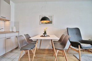 Una cocina moderna con una mesa de comedor, sillas, una lámpara colgante y un cuadro en la pared.