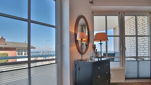 A room with large windows, a dresser, and a mirror.