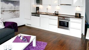 Una cocina moderna con armarios blancos, un microondas, una cafetera y un horno.