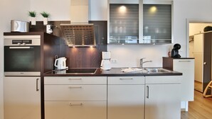 A modern kitchen with a built-in oven, a coffee maker, and a sink.