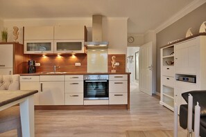 Une cuisine moderne avec des meubles en bois, un four encastré et une hotte en acier inoxydable.