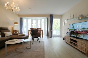 Una sala moderna con sofá, sillón, mesa de centro y televisor.