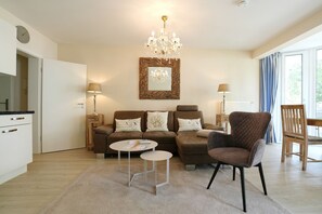 Ein Wohnzimmer mit Sofa, Sessel, Couchtisch und einer Pendelleuchte.