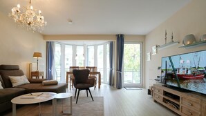 A modern living room with a sofa, armchair, coffee table, and a television. - Home by the Sea Apartment 9 - Home by the Sea (Timmendorfer Strand)