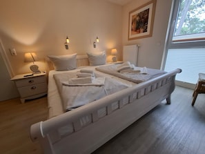 Ein Schlafzimmer mit einem Bett, Nachttischen, Lampen und einem Fenster.